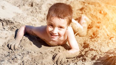 Biraz neşeli çocuk yaz tatilleri ve tatiller, oynar, gülümsüyor ve sıcak bir yaz gününde kumlu plaj boyunca geziniyor.