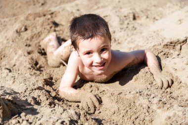 Biraz neşeli çocuk yaz tatilleri ve tatiller, oynar, gülümsüyor ve sıcak bir yaz gününde kumlu plaj boyunca geziniyor.