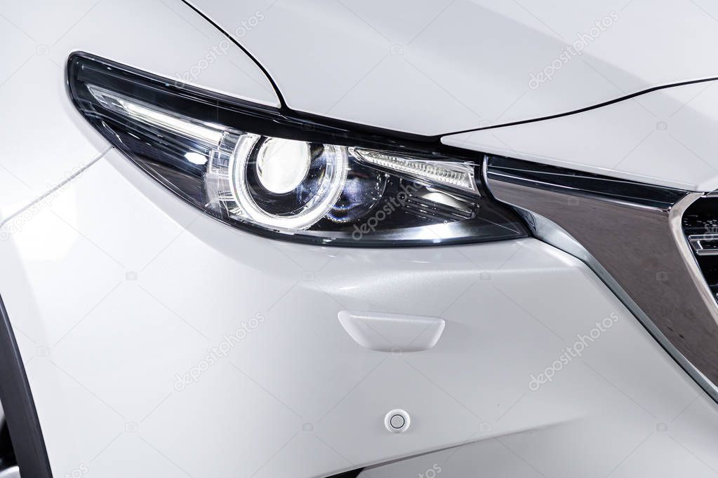 Close-up of c white car's front area with head light. 