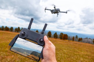 Quadrocopter üzerinde peyzaj. Genç bir adam elinde bir monitör ve dağların bir görüntü ile bir quadrocopter kontrol paneli tutar; arka planda bir quadrocopter olduğunu