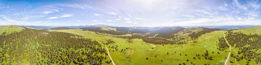 Panorama of the mountains  in Altai on a summer clear day. A landscape view of beautiful fresh green field   and  Altai mountain background.  Panoramic view of beautiful green field