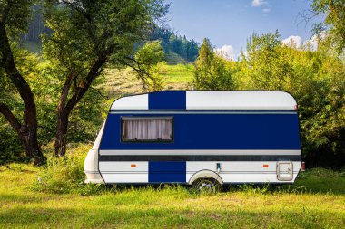 Bir araba römork, bir motor ev, Finlandiya ulusal bayrağı boyalı bir dağlık park halinde duruyor. Ülkeler arasında karayolu taşımacılığı, ticareti, ihracatı ve ithalatı kavramı. Arabayla seyahat