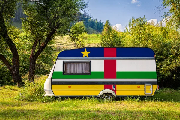 A car trailer, a motor home, painted in the national flag of Central African Republic  stands parked in a mountainous. The concept of road transport, trade, export and import between countries. Travel by car