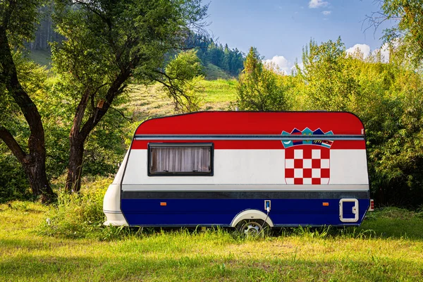 A car trailer, a motor home, painted in the national flag of Croatia stands parked in a mountainous. The concept of road transport, trade, export and import between countries. Travel by car