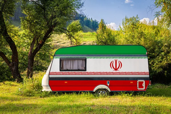 A car trailer, a motor home, painted in the national flag of Iran stands parked in a mountainous. The concept of road transport, trade, export and import between countries. Travel by car