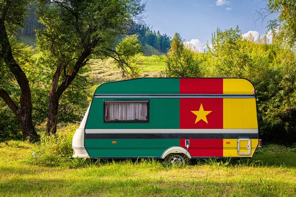 A car trailer, a motor home, painted in the national flag of Cameroon stands parked in a mountainous. The concept of road transport, trade, export and import between countries. Travel by car