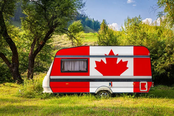 A car trailer, a motor home, painted in the national flag of Canada stands parked in a mountainous. The concept of road transport, trade, export and import between countries. Travel by car