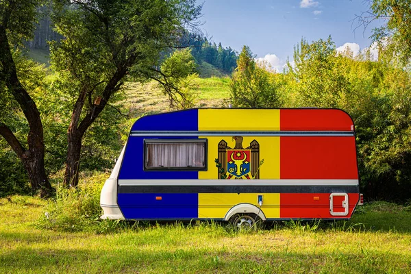 A car trailer, a motor home, painted in the national flag of Moldova stands parked in a mountainous. The concept of road transport, trade, export and import between countries. Travel by car
