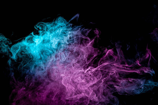 Abstract art colored blue and pink smoke on black isolated background. Stop the movement of multicolored smoke on dark backgroun