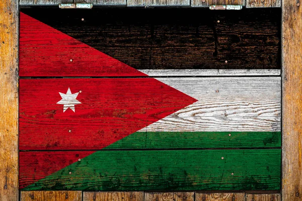 National flag of Jordan on a wooden wall background.The concept of national pride and symbol of the country.Flag painted on a wooden fence with metal nails.