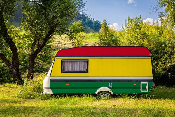 A car trailer, a motor home, painted in the national flag of  Bolivia stands parked in a mountainous. The concept of road transport, trade, export and import between countries. Travel by car
