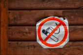 Nahaufnahme eines Rauchverbotsschildes an einer braunen Holzwand. das Konzept des Verbots und der Rauchentwöhnung