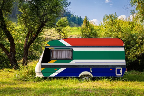 A car trailer, a motor home, painted in the national flag of  South African Republic stands parked in a mountainous. The concept of road transport, trade, export and import between countries. Travel by car