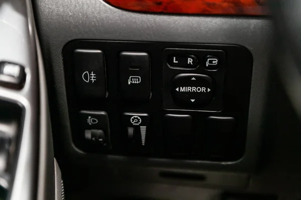 Close-up on the headlight , side mirror switch control buttons,  automatic adjust level dashboard. modern car interior: parts, buttons, knob