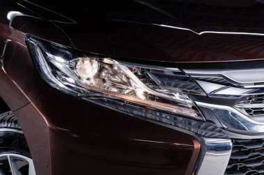 Novosibirsk, Rusya Temmuz 31, 2019: Mitsubishi Pajero Sport, yakın çekim kahverengi modern araba xenon lamba far, tampon, tekerlek.  