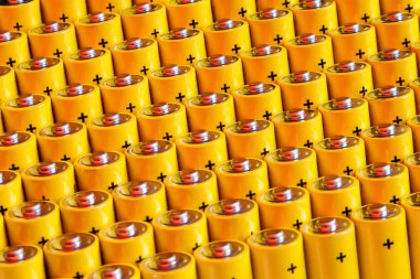 Alkalin pil aa boyutu. Birkaç pil sırayla. Aynı sarı pillerin yakın çekim, pozitif yüklertarafından eşit satırlar halinde dizilmiş. Enerji kullanımının güvenli olmayan bir yolu.