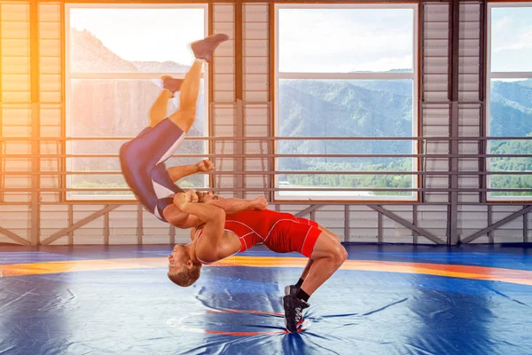 The concept of fair wrestling. Two greco-roman  wrestlers in red and blue uniform making a suplex wrestling  on a wrestling carpet in the gym.The concept of male wrestling and resistance