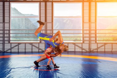 Spor taytlı küçük bir güreşçi çocuk spor salonunda güreş halısında yetişkin bir erkek güreşçi ile güreşir. Çocuk gücü ve dövüş sanatları eğitimi kavramı. Çocuklara Greko-Romen güreşini öğretmek