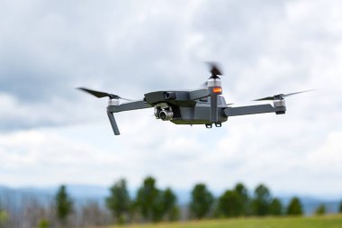 Dron helikopterini kamerayla kapatın. Quadcopter gökyüzü arka planda izole edilmiş. Güneşli bir günde mavi gökyüzü ve ormana karşı drone uçuş.