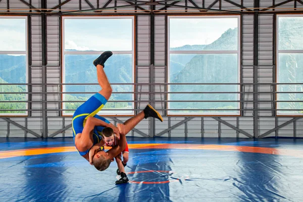 スポーツタイツのレスラー少年は ジムのレスリングカーペットの上で大人の男性レスラーと格闘します 子どもの力と武道の訓練の概念 子供たちにグレコローマレスリングを教える — ストック写真