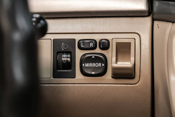 Close-up on the headlight and side mirror switch control buttons,  automatic adjust level dashboard. modern car interior: parts, buttons, knob