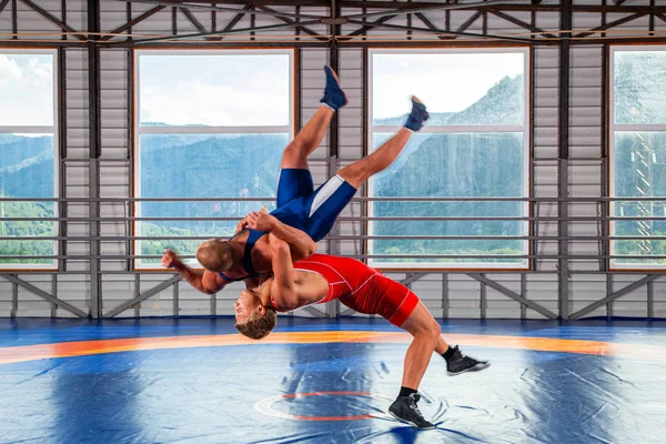 山を背景にレスリングマットで戦う伝統的なグレコローマンレスリング中にスポーツレスリングタイツとレスリングの2人の男性 レスラーは 彼の対戦相手の胸を通して投げる — ストック写真