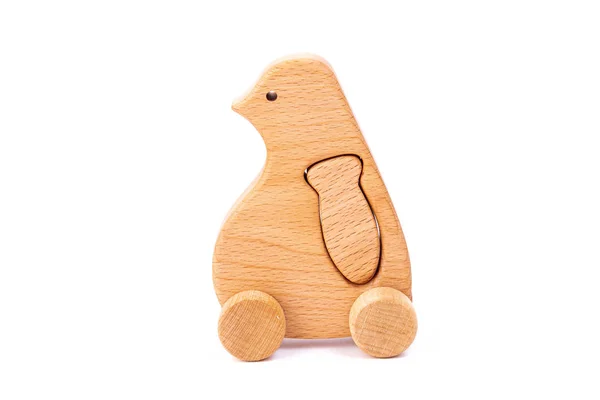 Photo of a wooden penguin with fish on wheels  of beech. Toy made of wood  on a white isolated background.A toy for entertaining children and resting parents