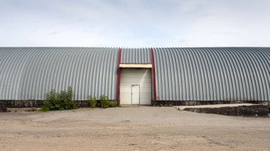 Metal gri panellerden yapılmış büyük endüstriyel bina cephesi. Malların taşınması, yüklenmesi ve depolanması nda endüstriyel kavram