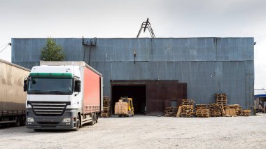 Teslim ve tedarik konsept görüntü. Yükleme alanındaki tesiste kamyonlar yükleniyor. Malların depolanması için büyük bir metal sanayi deposu . 