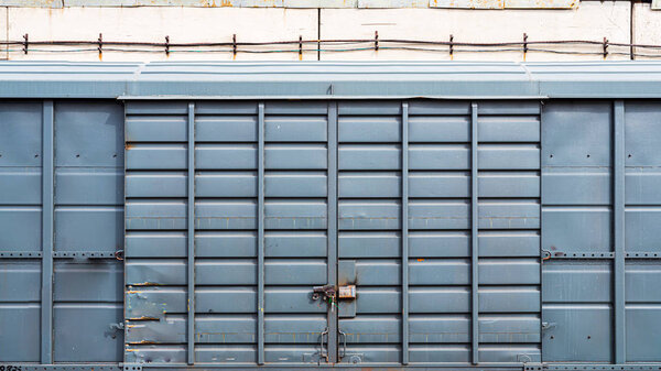Old metal door with a large padlock in a warehouse, garage. Front view of a blue container