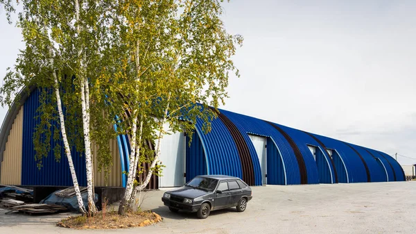 Facade on large industrial building made of metal white and blue panels. Industrial concept of transportation, loading and storage of goods. The car is in the loading area