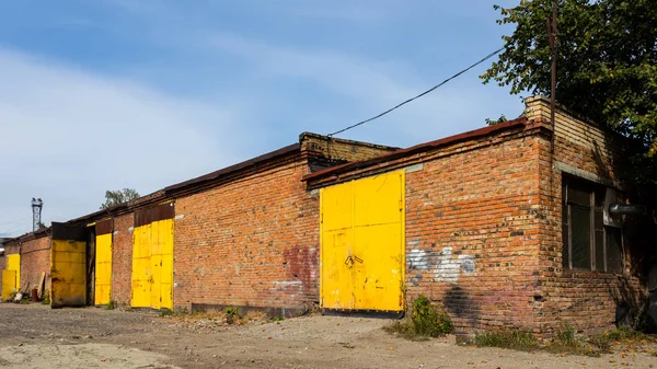 Facade of a yellow metal warehouse, a commercial building with entrances for cars for storing goods. The concept of storage of goods by importers, exporters, wholesalers, transport enterprises, customs