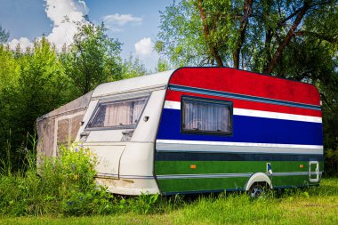 Bir araba römork, bir motor ev, Gambiya ulusal bayrağı boyalı bir dağlık park halinde duruyor. Ülkeler arasında karayolu taşımacılığı, ticareti, ihracatı ve ithalatı kavramı.