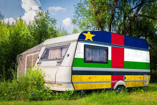 A car trailer, a motor home, painted in the national flag of  Central African Republic stands parked in a mountainous. The concept of road transport, trade, export and import between countries.