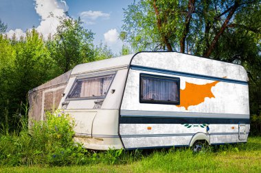 Bir araba römork, bir motor ev, Kıbrıs ulusal bayrağı boyalı bir dağlık park halinde duruyor. Ülkeler arasında karayolu taşımacılığı, ticareti, ihracatı ve ithalatı kavramı.