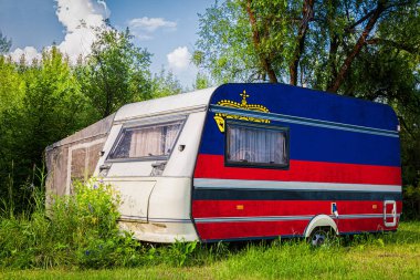 Bir araba römork, bir motor ev, Liechtenstein ulusal bayrağı boyalı bir dağlık park halinde duruyor. Ülkeler arasında karayolu taşımacılığı, ticareti, ihracatı ve ithalatı kavramı.