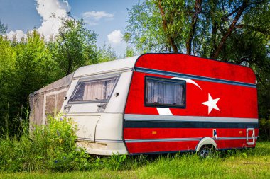 Türkiye'nin ulusal bayrağına boyanmış bir araba römorku, bir motorlu ev, dağlık bir park halinde duruyor. Ülkeler arasında karayolu taşımacılığı, ticareti, ihracatı ve ithalatı kavramı.
