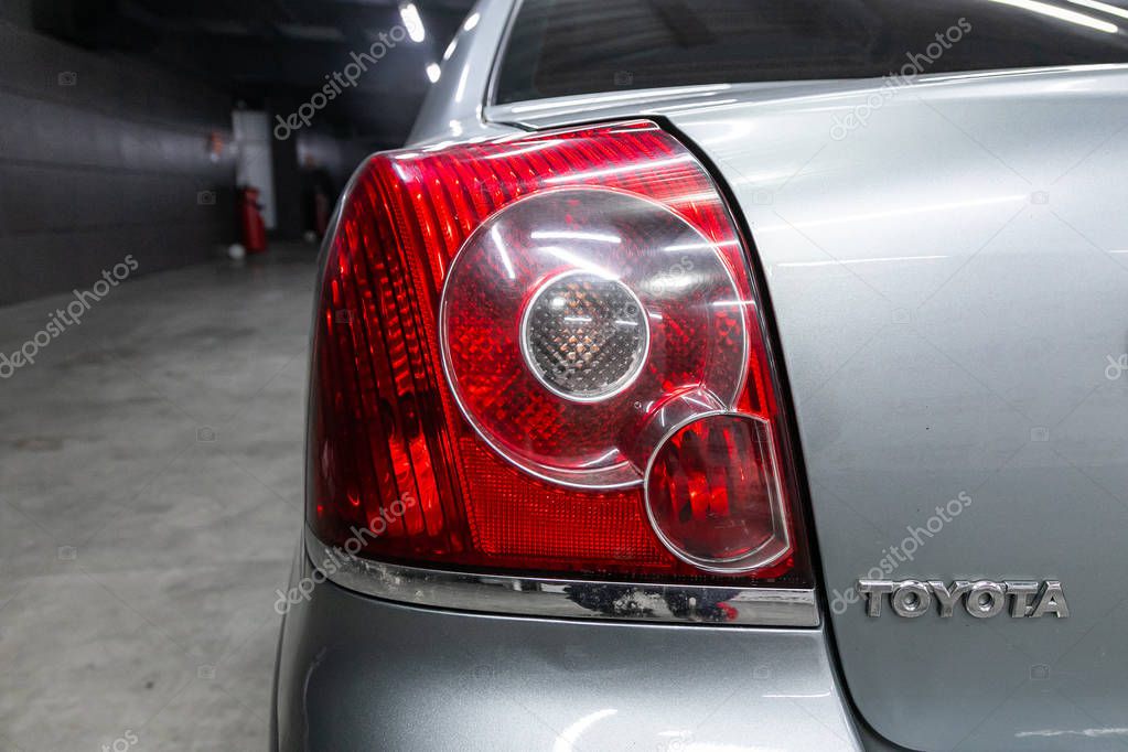 Novosibirsk, Russia  September 18, 2019:  close-up, the back of the car is a headlight, a bumper, a back cover of a baguette and an Toyota nameplate on a black plastic steering wheel.