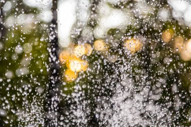 Güneş ışınlarının altında mavi bir zemin üzerinde bir sürü damla ve kabarcık olan su püskürtüleri. Büyük bir plan Büyük bir çeşmenin su dalgalarının dokusu