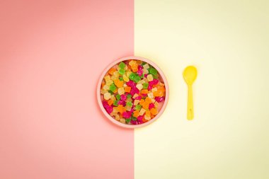 Minimalist düz şekerlenmiş ananas kurutulmuş dilimleri ve sarı-pembe izole arka plan sarı bir kaşık ile plastik pembe bir tabak ile yatıyordu. Metin, moup için yer ile Plastik gıda.   