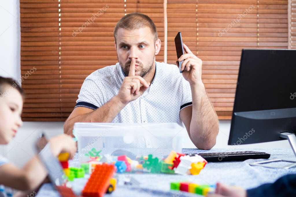 Young father business man parent interrupts by her kids sons while talking on the phone and working in the  home. Online working and bringing up children at same time.