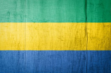Gabon 'un ulusal bayrağı eski kıyafetlerin üzerinde boya renkleriyle tasvir ediliyor. Kumaş dokusu arka planında bayrak pankartı.