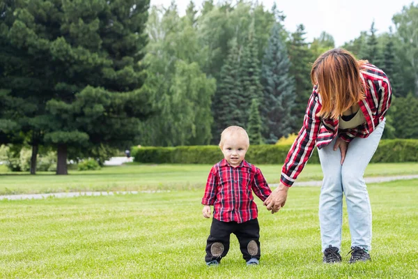 Anya Segít Kisfiának Megtenni Első Lépéseket Zöld Mezőn Parkban Egy — Stock Fotó