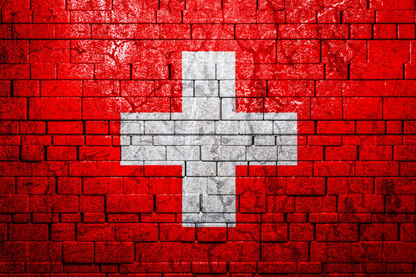 National flag of Switzerland on brick  wall background.The concept of national pride and symbol of the country. Flag  banner on  stone texture background.