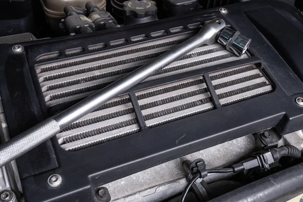 Metal ratchet  under the hood of the car on an oil cooler. Concept of car repair and tools in car service