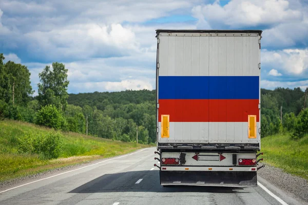 A  truck with the national flag of Russia depicted on the back door carries goods to another country along the highway. Concept of export-import,transportation, national delivery of goods