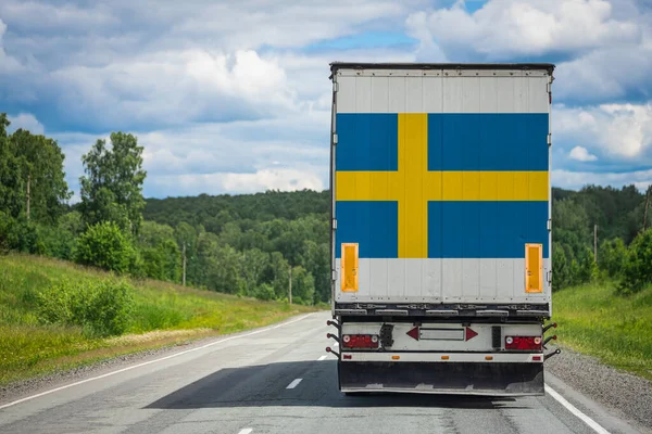 A  truck with the national flag of Sweden depicted on the back door carries goods to another country along the highway. Concept of export-import,transportation, national delivery of goods