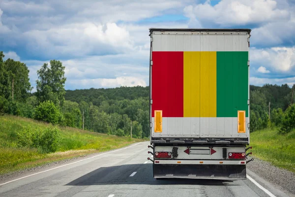 A  truck with the national flag of Guinea depicted on the back door carries goods to another country along the highway. Concept of export-import,transportation, national delivery of goods