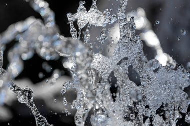 Su damlalarının mavi bir gradyan zemin üzerinde, su yoğunlaşması damlacıklarıyla kaplı bir şekilde kapanması. Yukarıya doğru uçan bir çeşmenin yakın çekimi