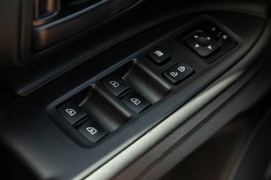 Yeni arabadaki bir kapı kontrol paneline yakın çekim. Pencere kontrol paneli, kapı kilidi düğmesi ve ayna kontrollü kol dinlenmesi.